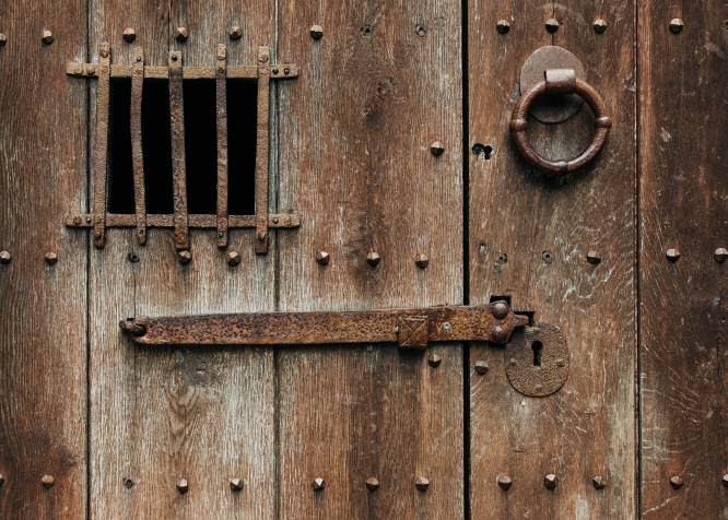 zdjęcie zamkniętych bardzo starych drzwi z zardzewiałą zasuwą